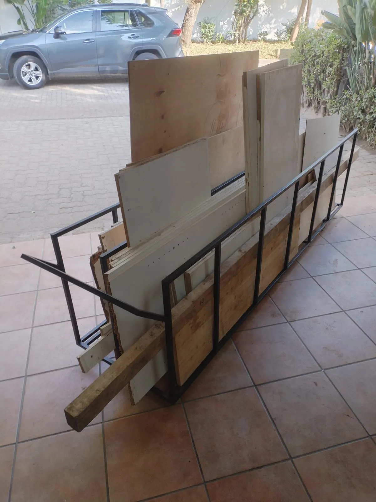 A-frame steel board rack in use, loaded with sheets of board and lengths of timber