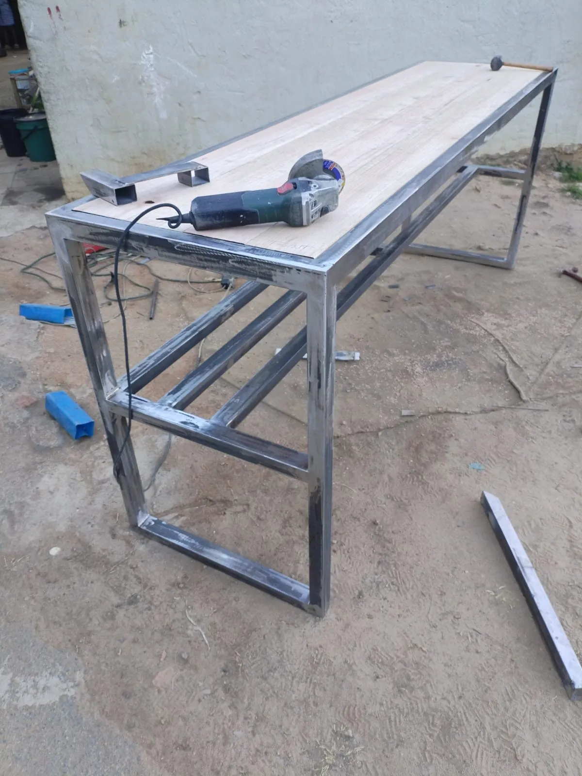 The console table part-built: bare welded steel frame with the raw, unfinished hardwood top resting in place