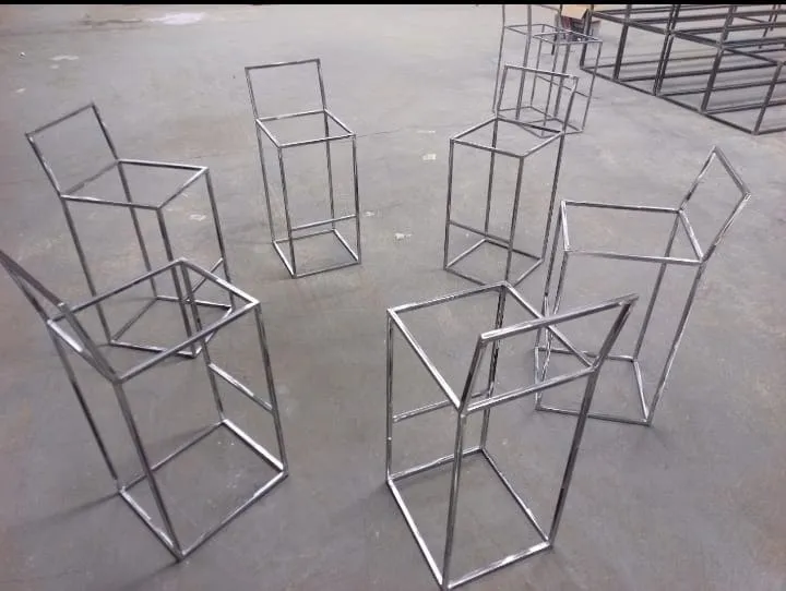 A batch of mild steel stool frames grouped together on a workshop floor, all built to the same pattern