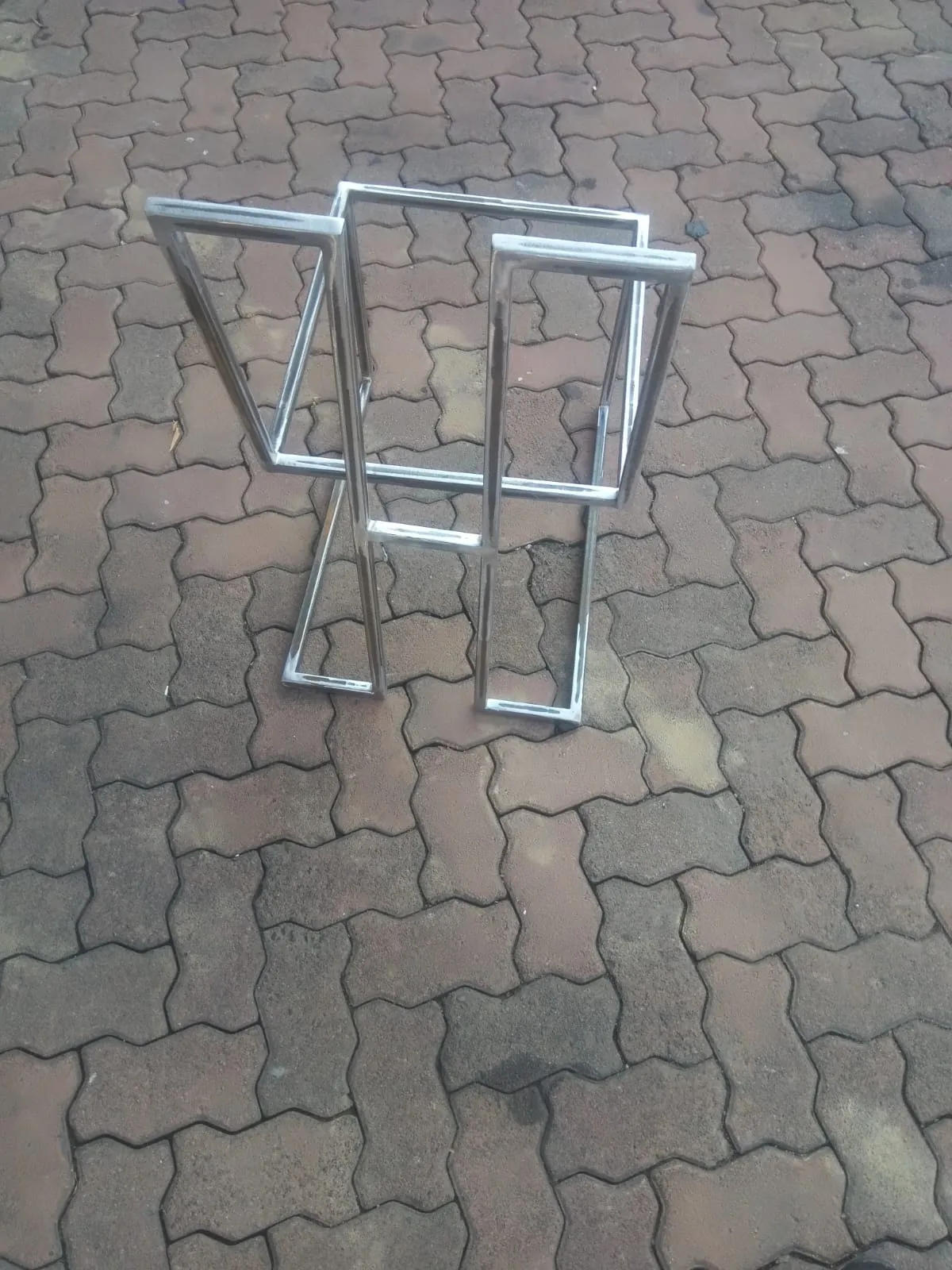 Mild steel table base with angled legs and a square top frame, welds ground bright, on paving